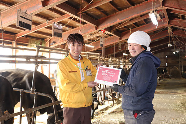 山本牧場・山本さんにメッセージを渡す宅配職員の写真