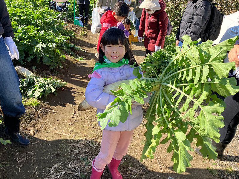 だいこんを持ち、笑顔を見せる参加者