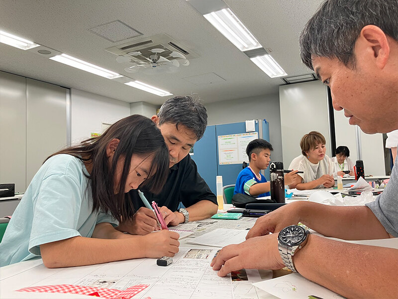 記者からタイトルの作り方についてアドバイスを受ける子どもとお父さんの様子